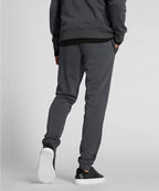Man wearing dark gray sweatpants and black shoes on a light gray background RYU