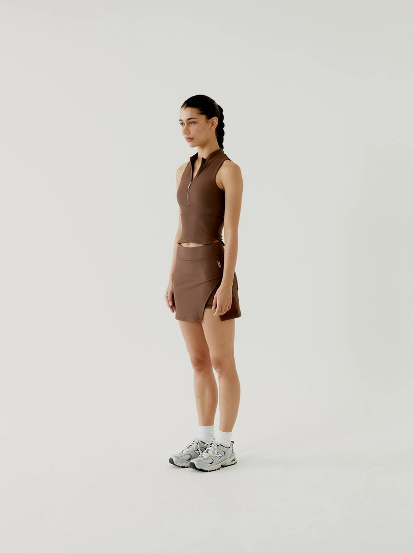 Woman wearing a brown sleeveless top and skirt set on a white background