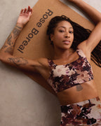Woman in Rose Boreal floral sports bra and leggings lying on a 'Rose Boreal' mat