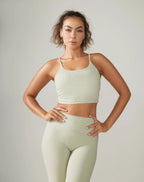 Woman wearing a light green sports bra and leggings set against a plain background Rose Boreal