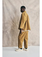 Person wearing a mustard yellow outfit standing against a plain background Devlyn van Loon 