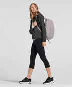 Woman wearing black athletic outfit with a gray backpack on a light gray background RYU