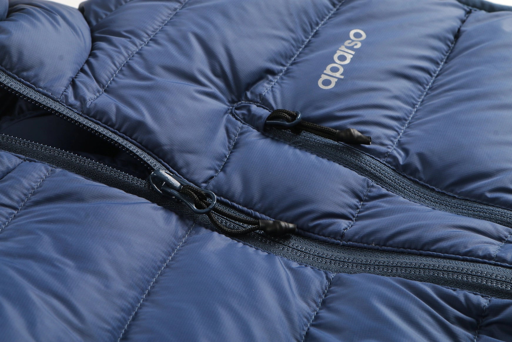 Close-up of a blue puffer jacket with a brand logo on the chest. Aparso