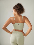 Woman wearing a light green sports bra and leggings against a neutral background Rose Boreal