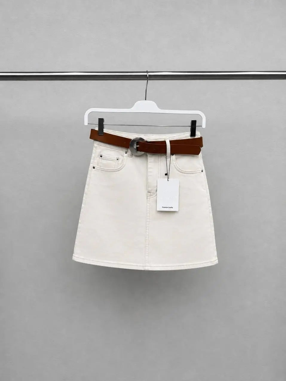 Ecru denim mini skirt with brown leather belt on hanger product view - ANAZ Denim Mini Skirt with Belt