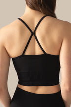 Black sports bra with criss-cross straps worn by a person on a neutral background