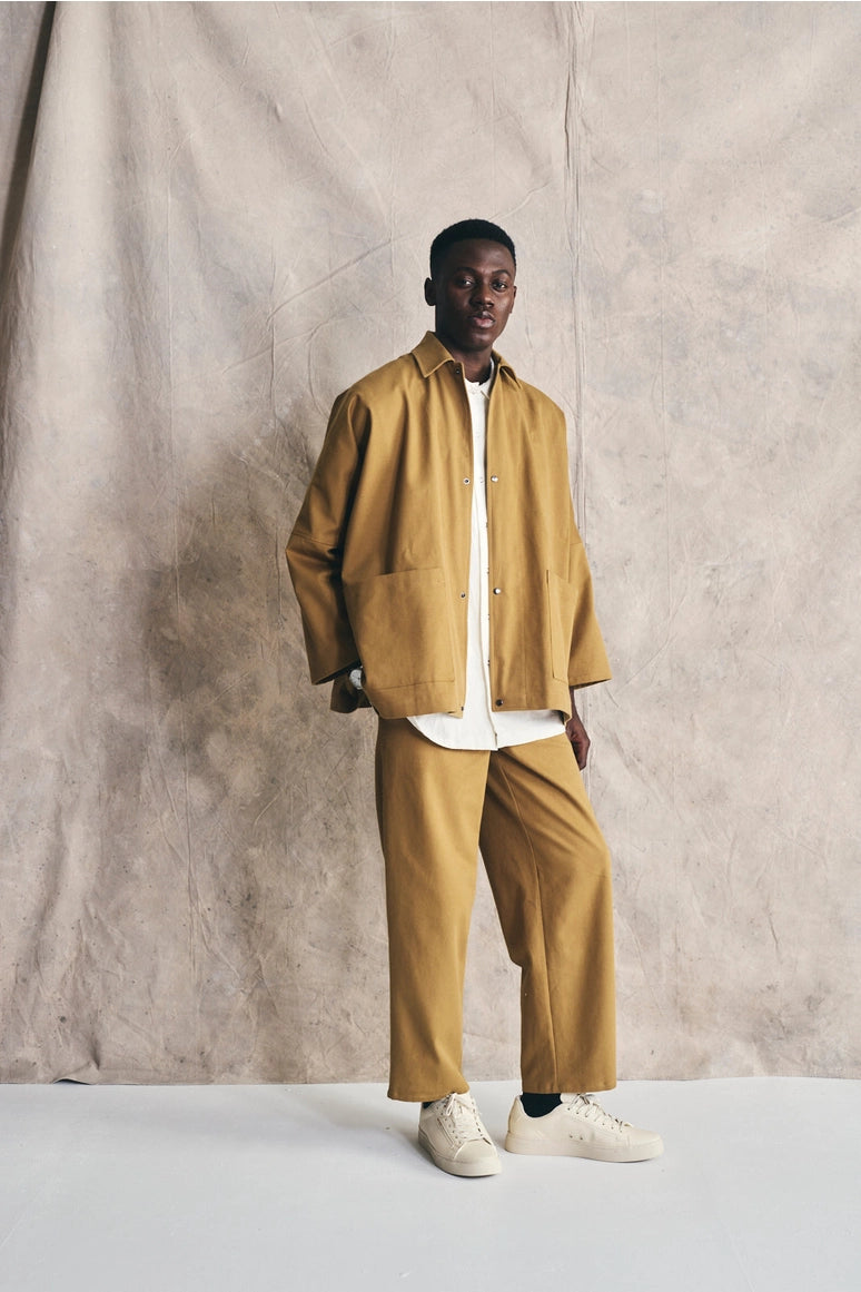 Man wearing a mustard yellow jacket and pants against a plain background Devlyn van Loon 