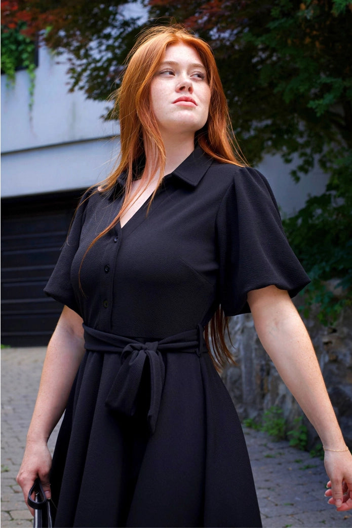 Woman wearing a black dress with a blurred background ANNICK