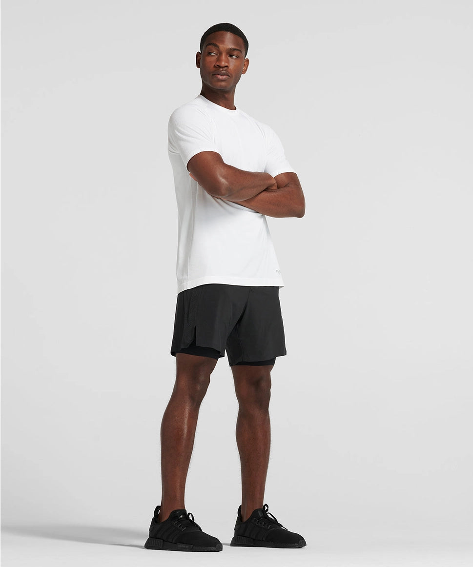 Man wearing a white t-shirt and black shorts standing against a plain background RYU