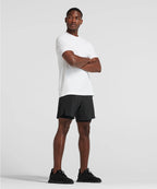 Man wearing a white t-shirt and black shorts standing against a plain background RYU