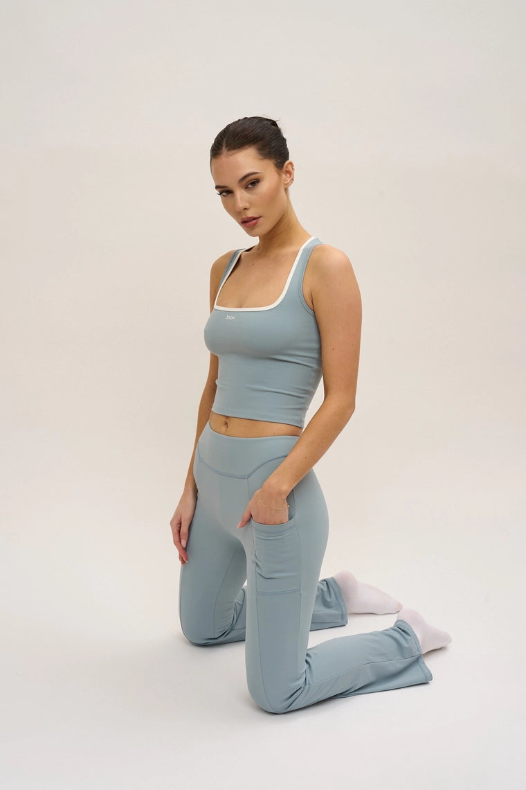 Woman wearing a light blue athletic outfit on a plain background