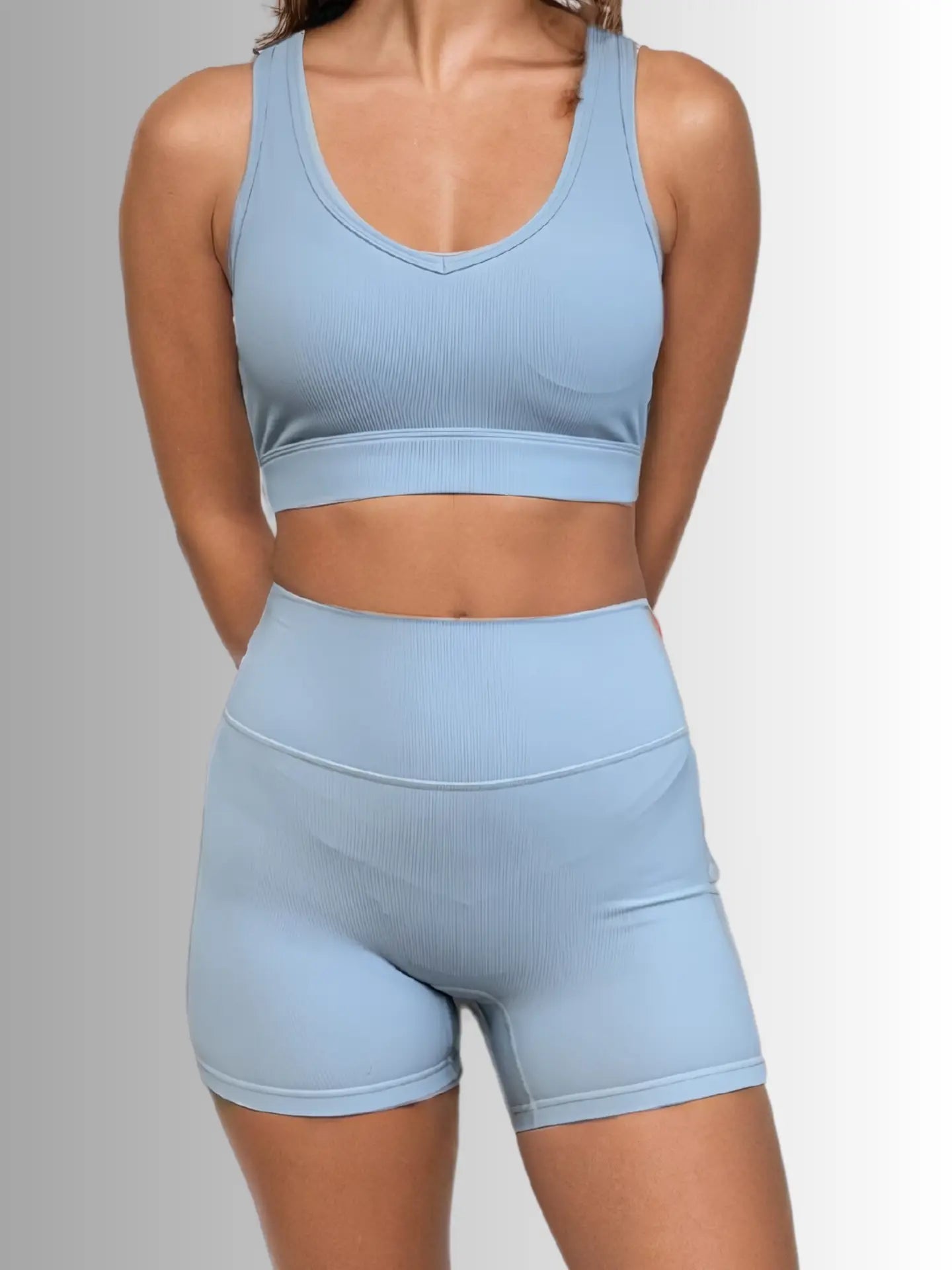 Light blue athletic outfit with sports bra and shorts on a gray background PRIV
