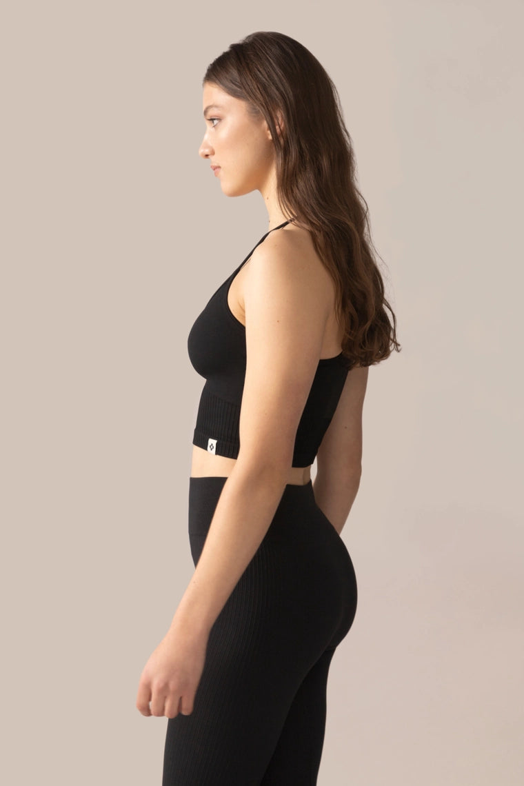 Woman wearing a black athletic outfit on a beige background