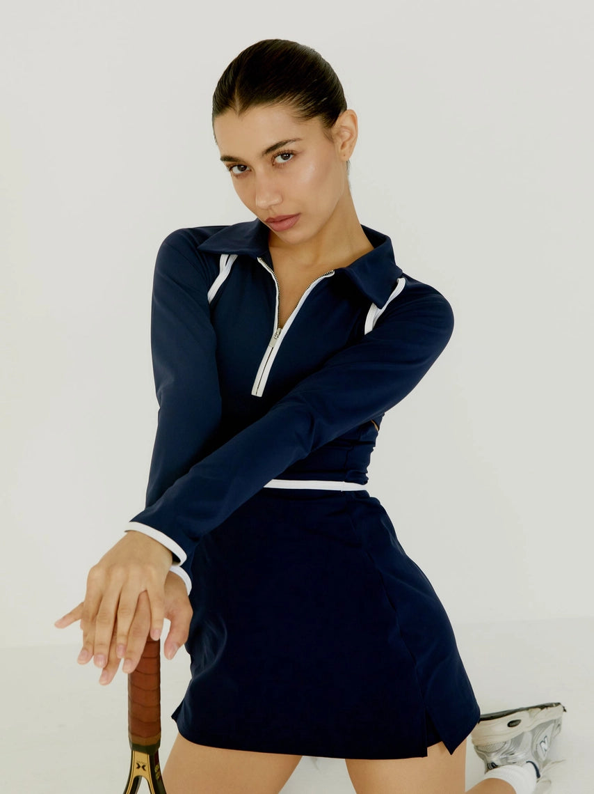 Woman in BOV navy blue outfit with white accents posing against a plain background