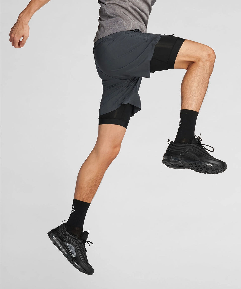 Man wearing black athletic shorts and shoes on a light gray background