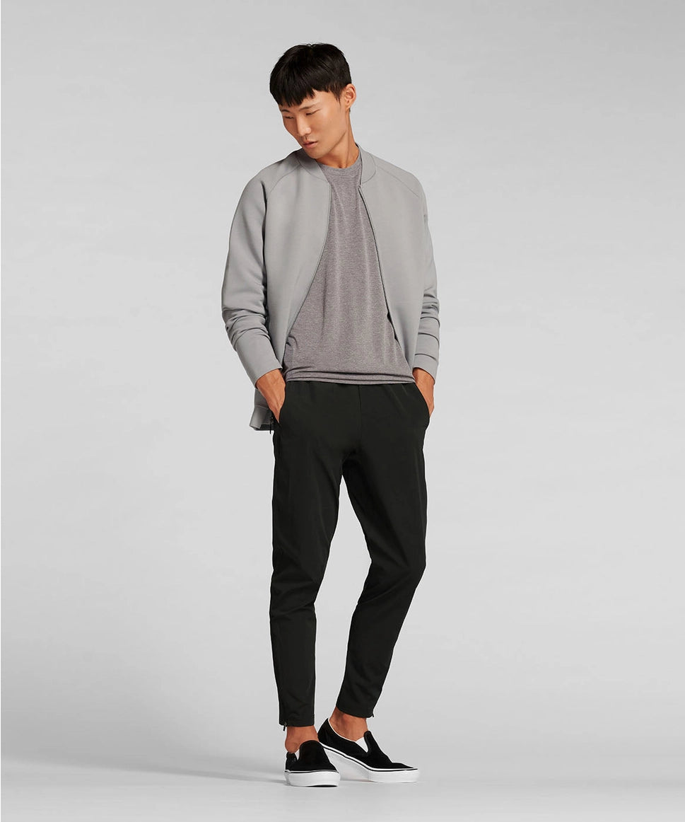 Man wearing a gray sweater and black pants on a light gray background RYU