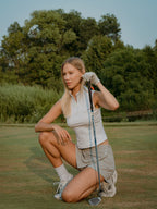 Woman on a golf course holding a golf club in a grey BOV skirt