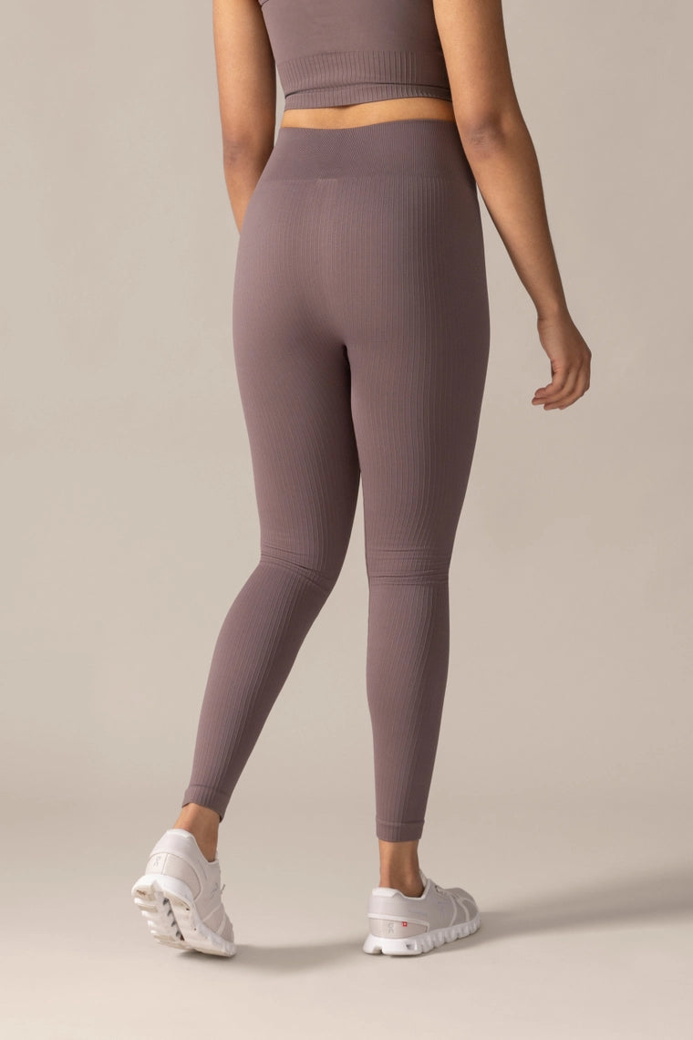 Women wearing mauve leggings and a matching crop top on a beige background