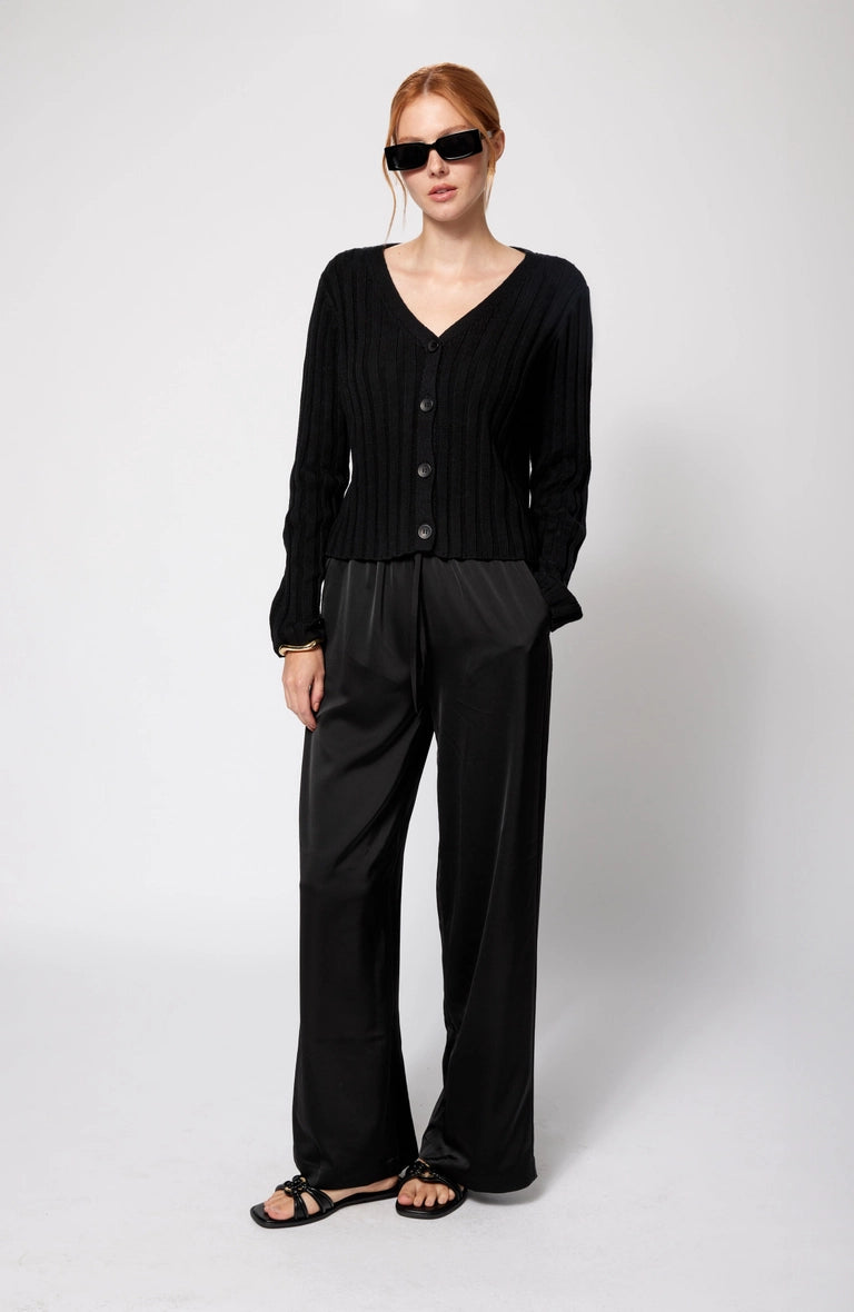 Woman wearing a black cardigan and pants on a white background Amanda Maria