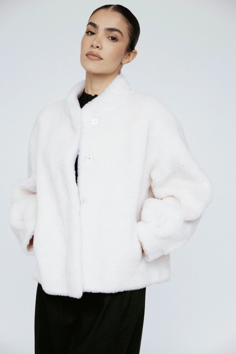 Woman wearing a white fur coat against a white background