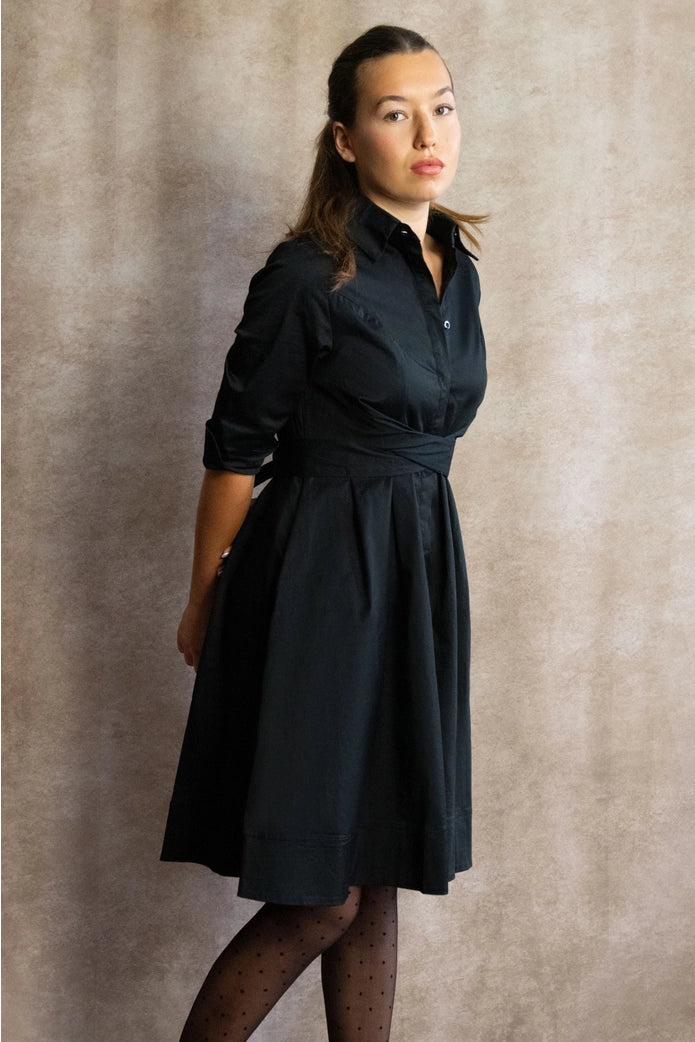 Woman wearing a black dress against a plain background ANNICK