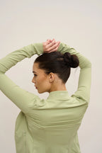 Person wearing a light green long-sleeve top against a plain background