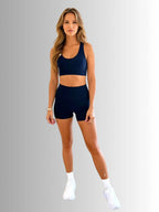 Woman wearing a navy sports bra and shorts set on a gray background PRIV