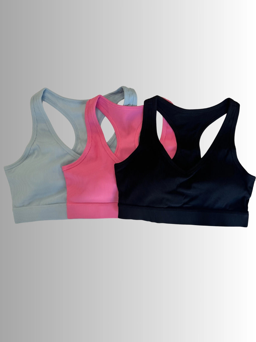 Three sports bras in gray, pink, and black on a light gray background PRIV