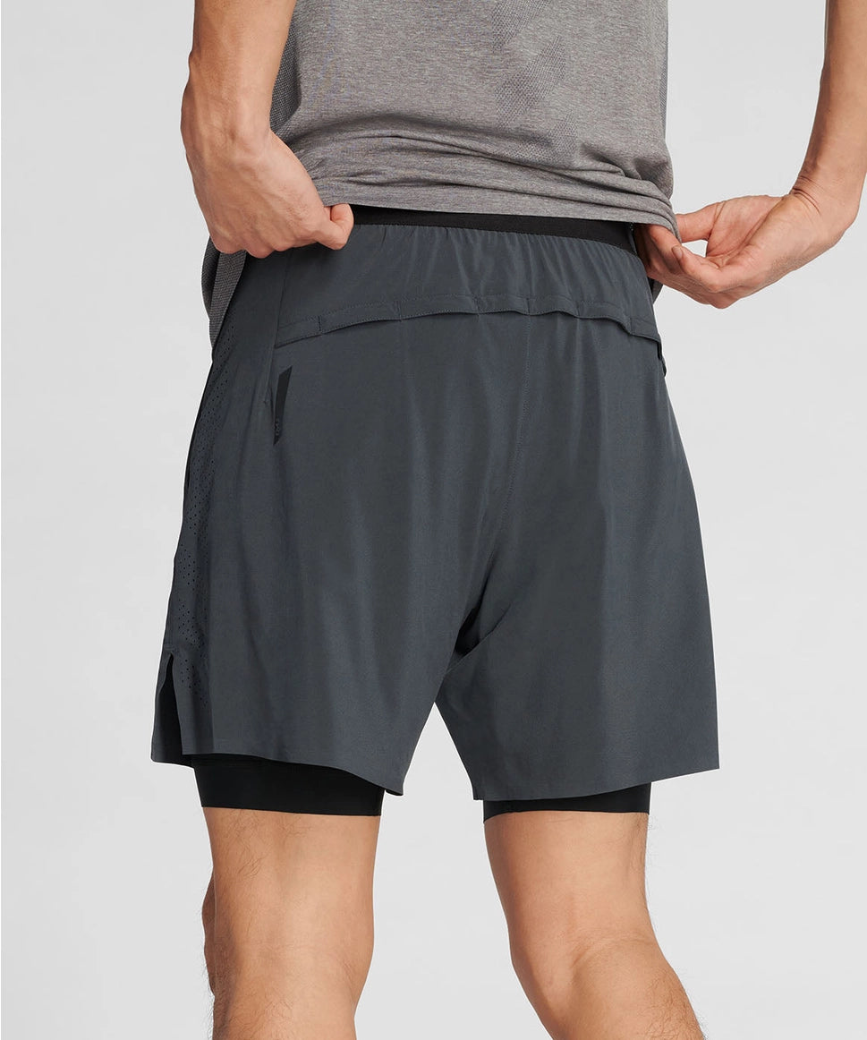 Man wearing gray athletic shorts and a gray shirt on a light gray background RYU