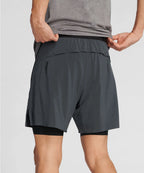 Man wearing gray athletic shorts and a gray shirt on a light gray background RYU