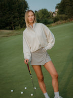 Woman on a golf course holding a golf club with golf balls on the ground.