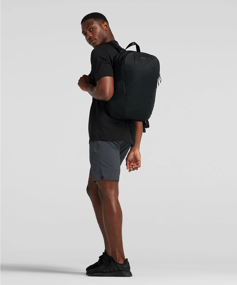 Man wearing a black backpack on a light gray background RYU