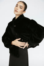 Woman wearing a black coat against a white background Amanda Maria