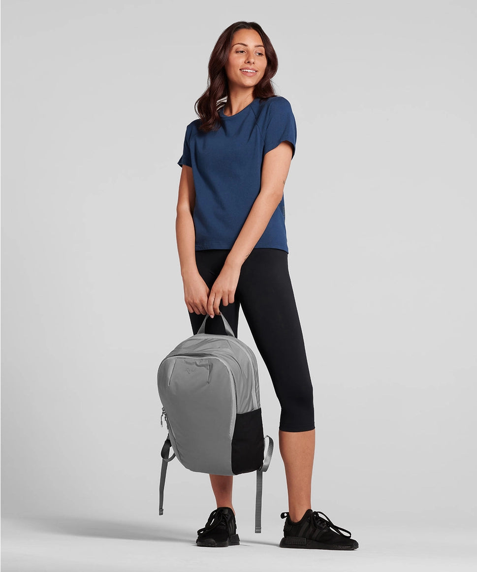 Woman holding a gray backpack against a plain background RYU