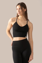 Woman wearing a black sports bra and leggings against a beige background