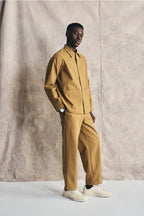 Man wearing a mustard yellow outfit against a plain background Devlyn van Loon 