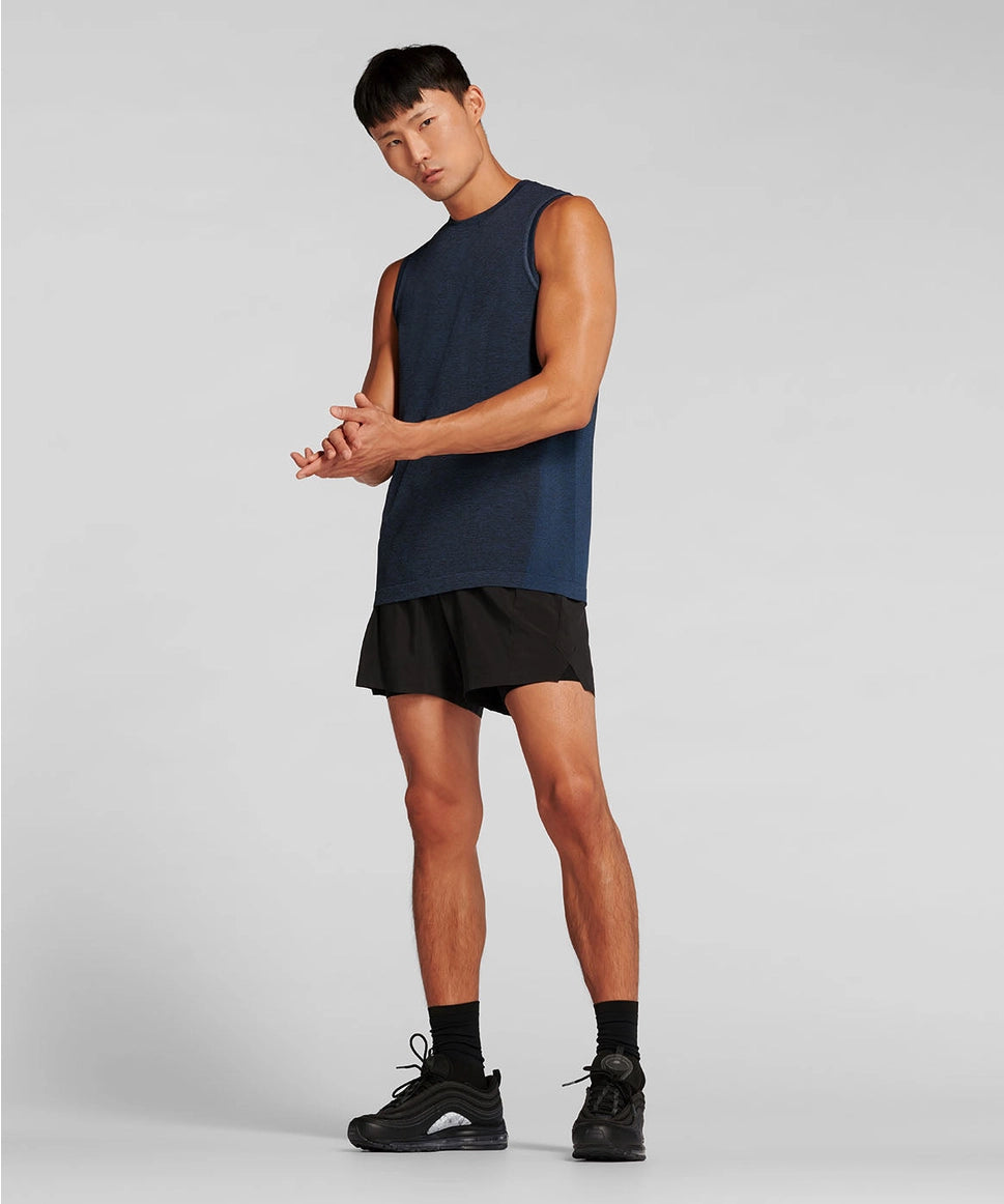 Man wearing a navy sleeveless shirt and black shorts on a gray background RYU