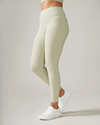 Women wearing light green leggings and white sneakers on a plain background Rose Boreal