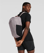 Person wearing a gray and black backpack against a plain background RYU