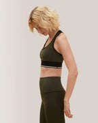 Woman wearing a green sports bra and leggings on a plain background Rose Boreal