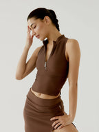 Woman wearing a brown bov sleeveless top and skirt against a plain background
