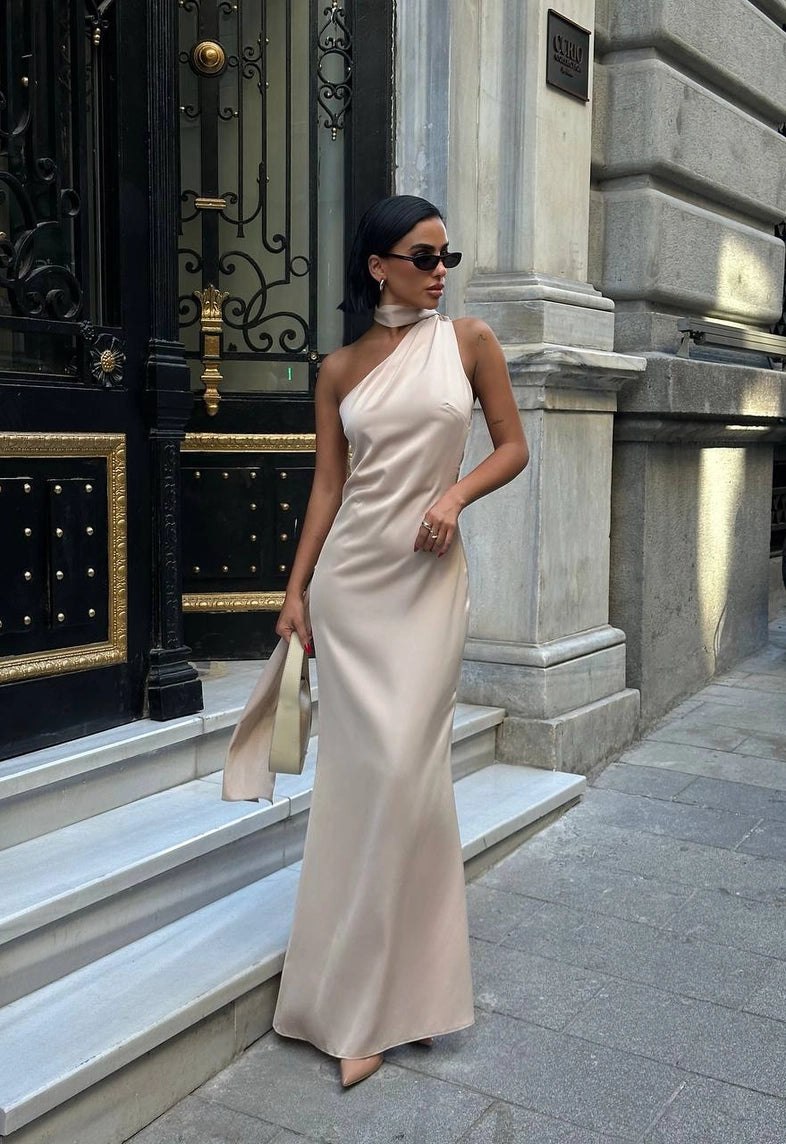 Woman in a white one-shoulder dress standing in front of a building entrance. Standpoint Top