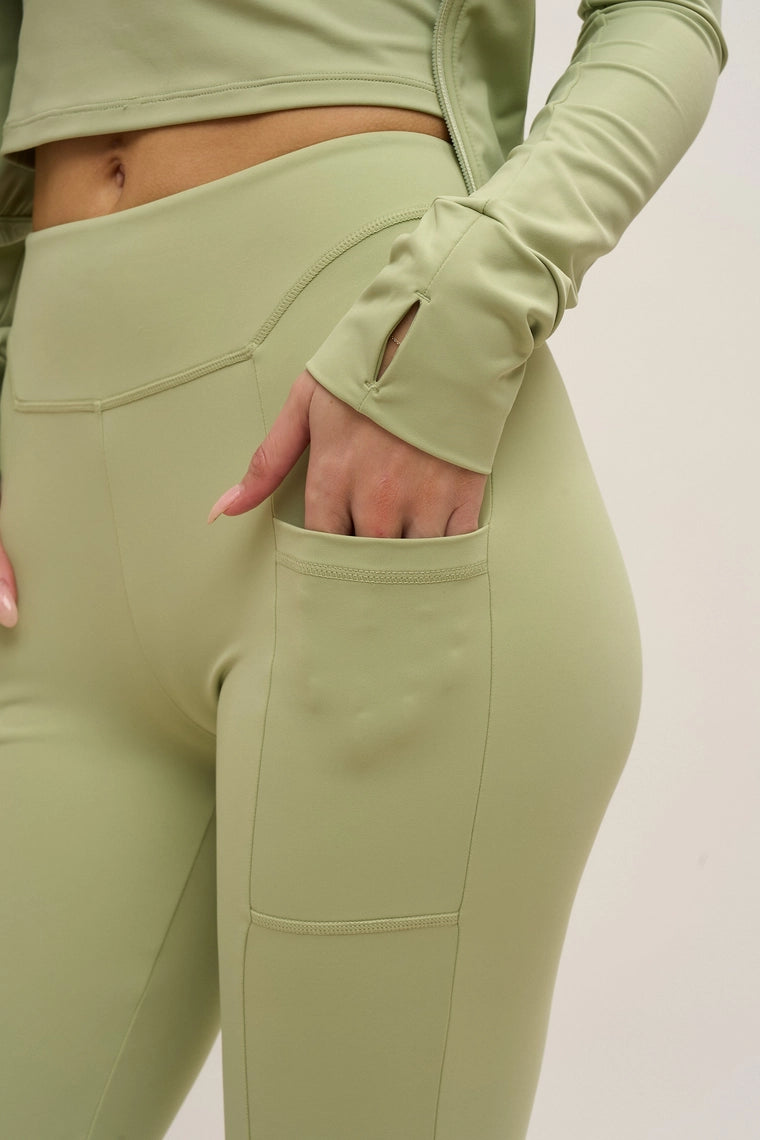 Green athletic outfit with leggings and long-sleeve top on a plain background