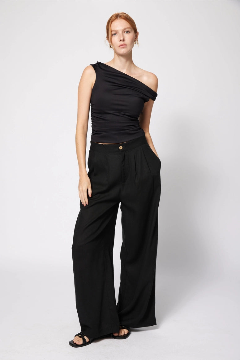Woman wearing a black one-shoulder top and wide-leg pants on a white background Amanda Maria