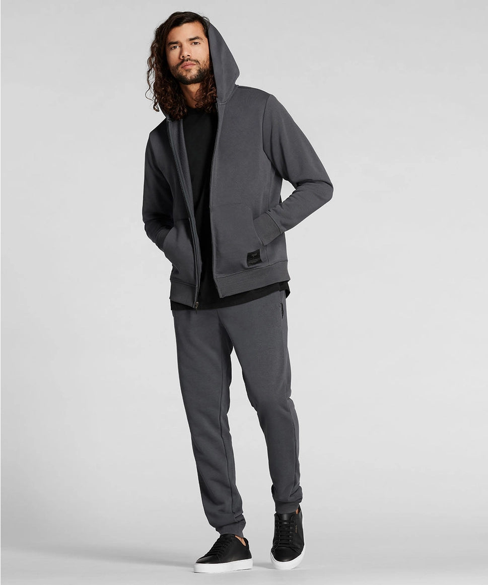 Man wearing a gray hoodie and pants on a light gray background RYU