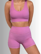 Women wearing a pink sports bra and shorts set on a gray background PRIV