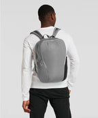 Person wearing a gray backpack on a plain background RYU