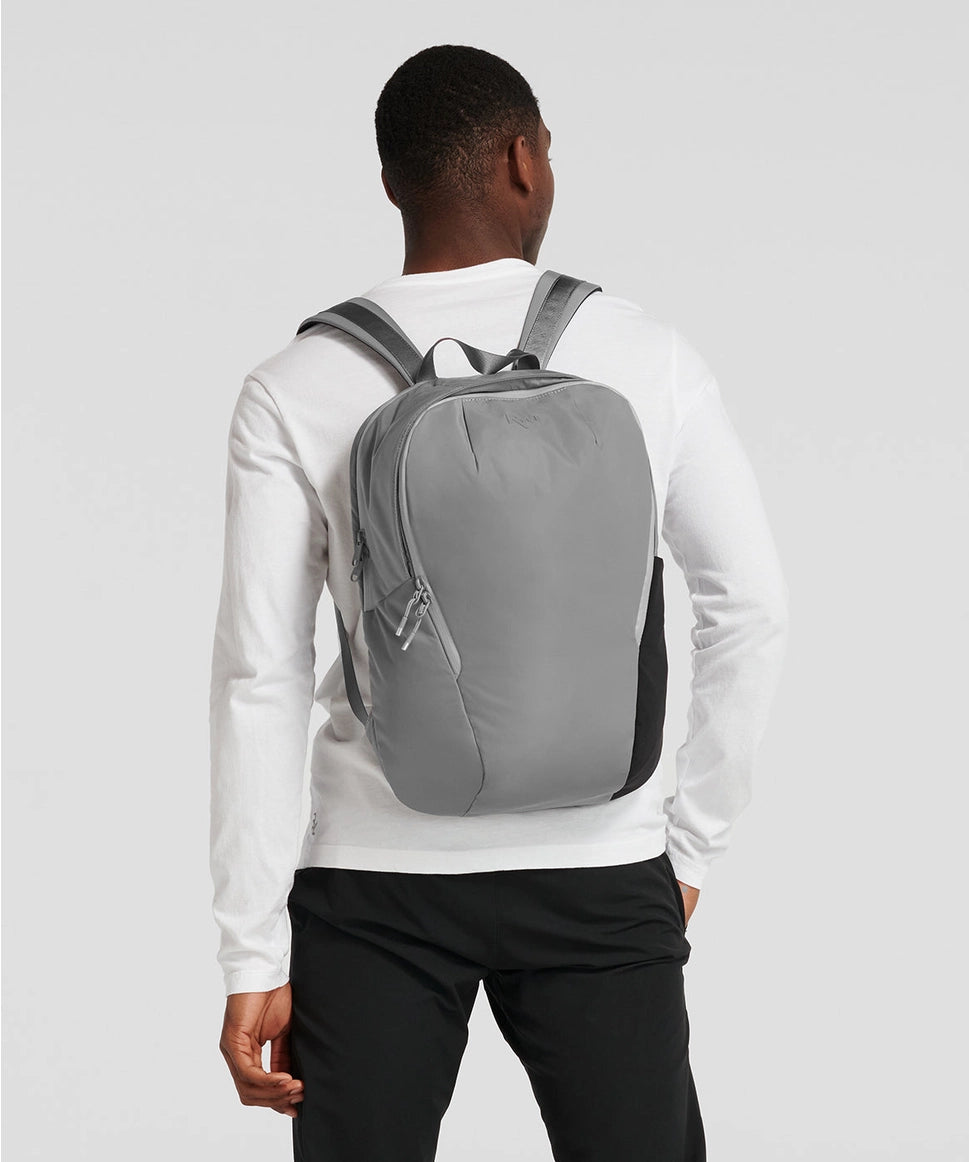 Person wearing a gray backpack on a plain background RYU