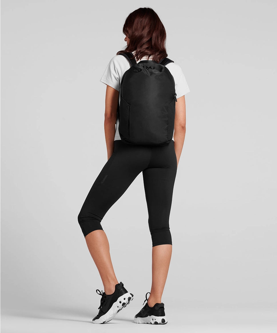 Person wearing a black backpack on a light gray background RYU