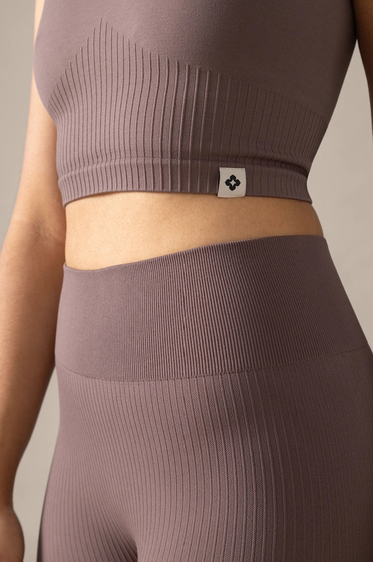 Brown ribbed athletic top and leggings with a brand logo on a neutral background